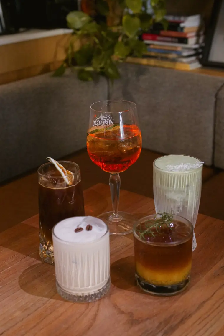 Aperol spritz, espresso Alexander, espresso tonic, maracuyá cold brew y coco matcha sobre una mesa de madera