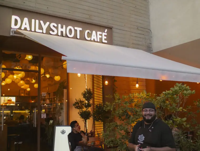 Fachada de Dailyshot Café con su terraza al atardecer